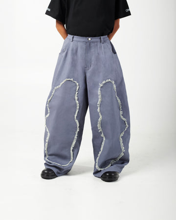 Model wearing AABELI denim pants with tassel detailing and pleats at the front and back, and GOMD Tee with a logo on the left sleeve.
