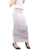"Woman wearing a white top and long white skirt on a white background"
