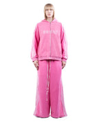 Person wearing a pink tracksuit with brand logo on a white background