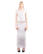 Woman wearing a white sleeveless top and long skirt on a white background