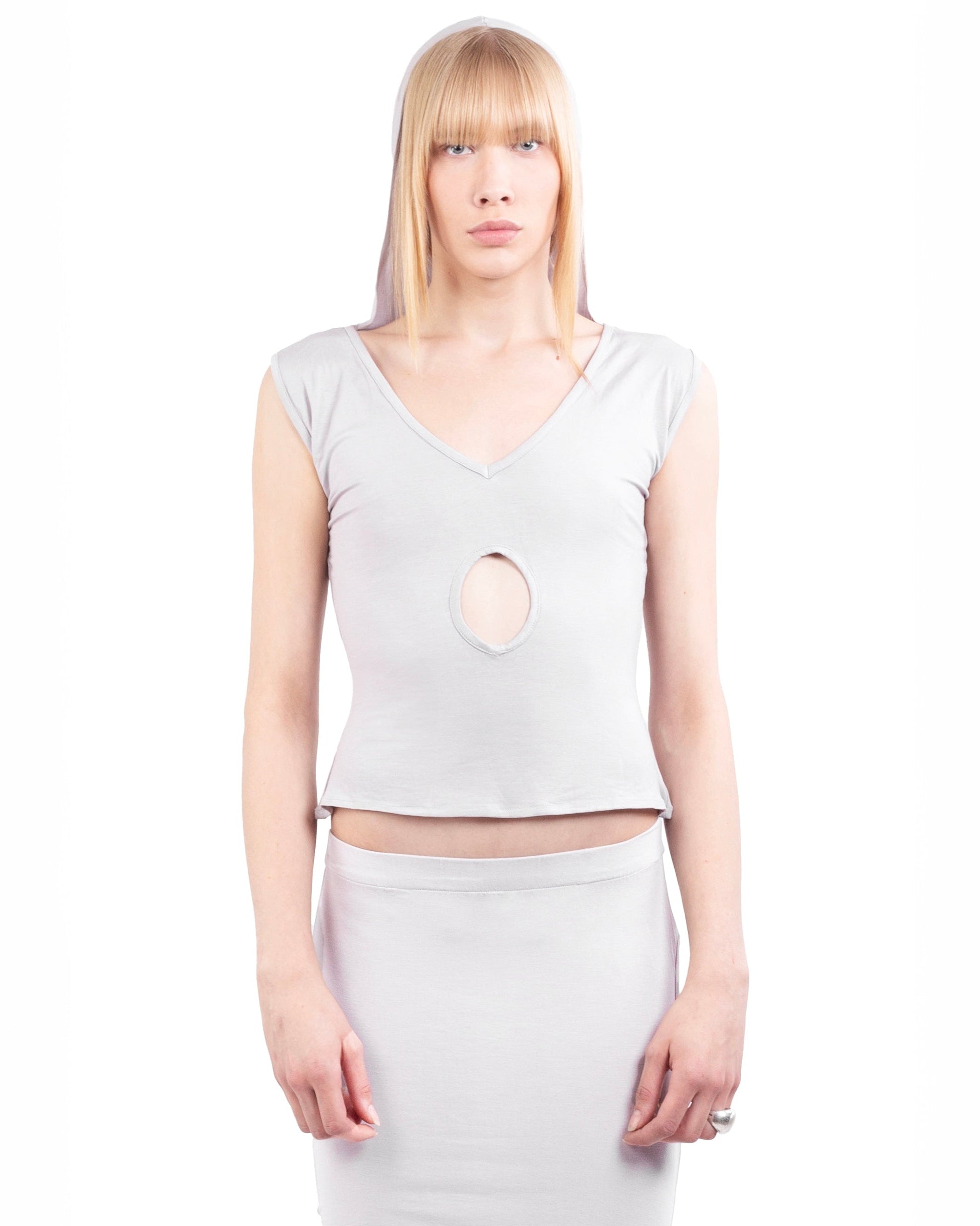 Woman wearing a light gray sleeveless top with a cutout design on a white background
