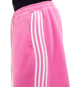 Pink sweatpants with white stripes worn by a person on a white background