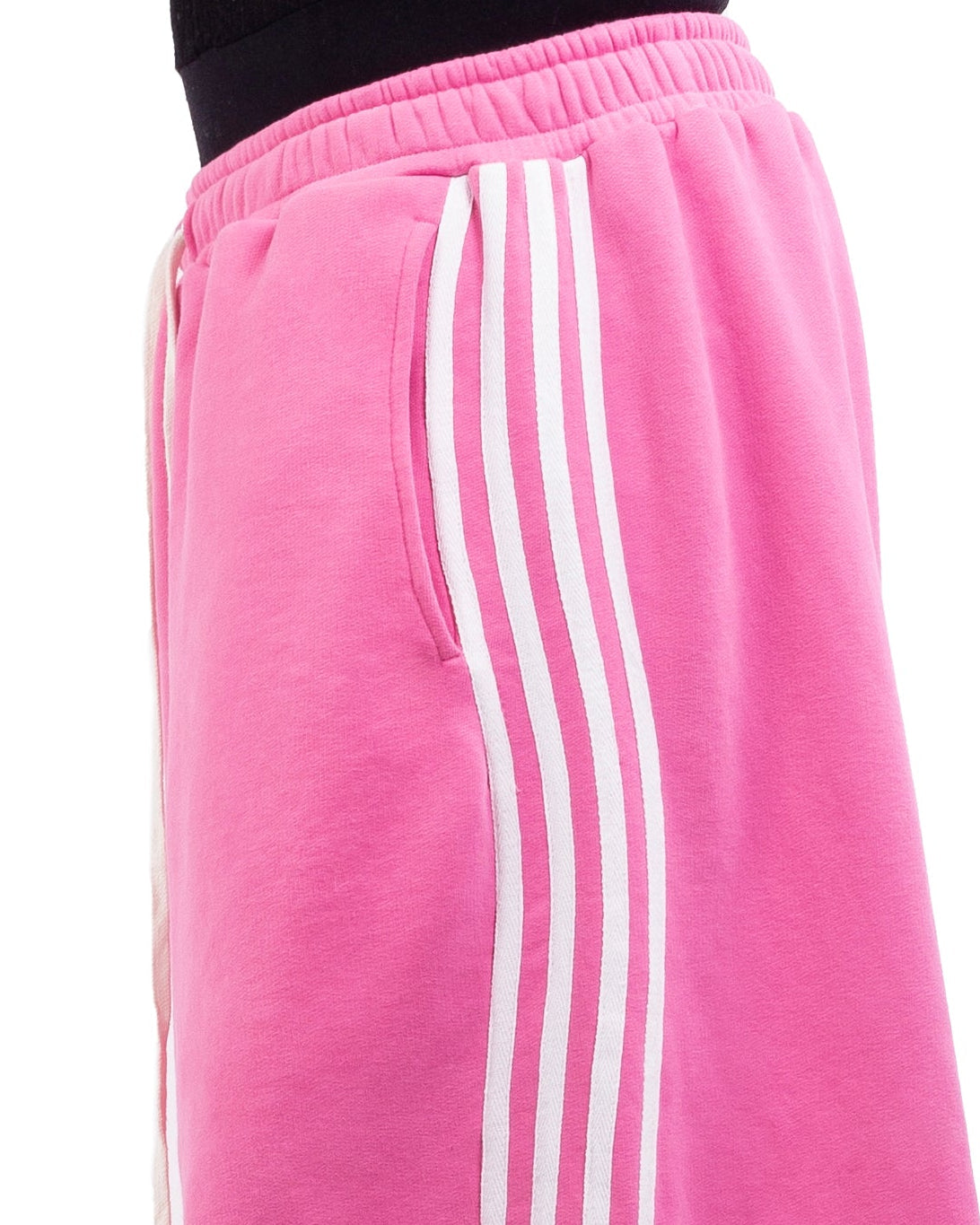 Pink sweatpants with white stripes worn by a person on a white background