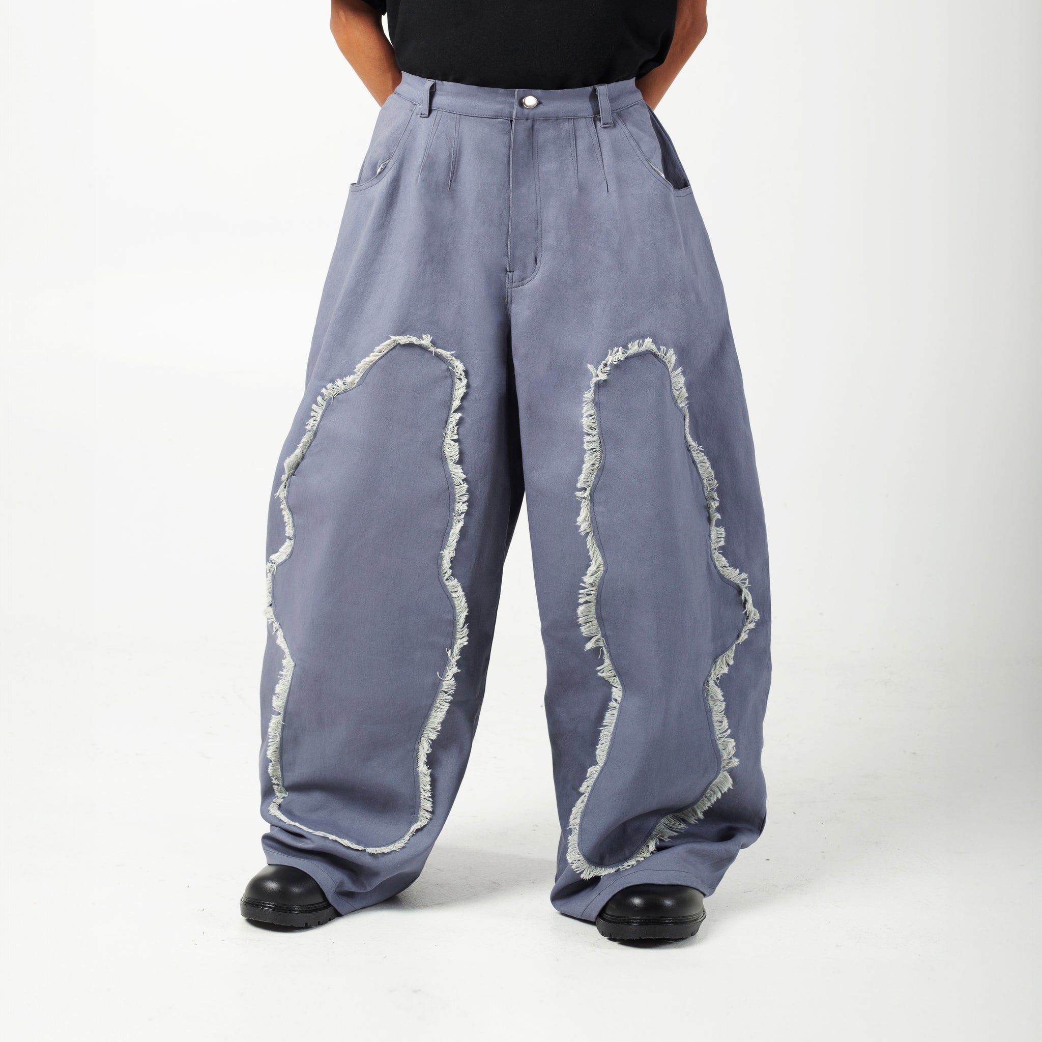 Model wearing AABELI denim pants with tassel detailing and pleats at the front and back, and GOMD Tee with a logo on the left sleeve.