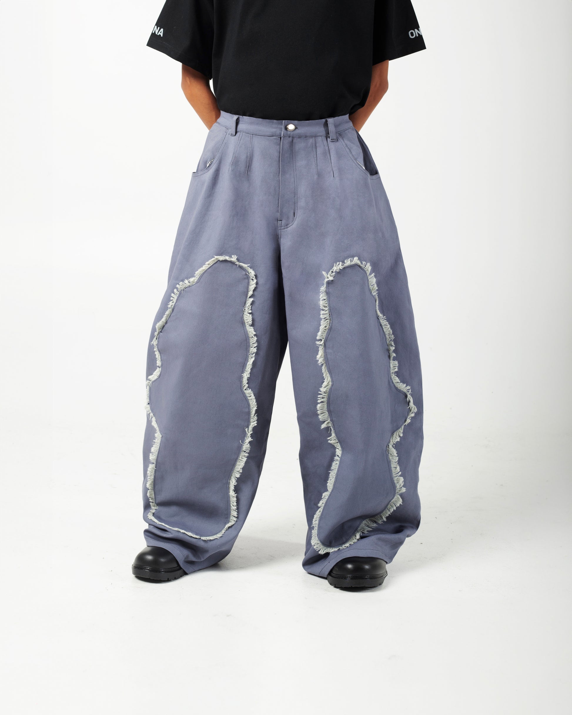 Model wearing AABELI denim pants with tassel detailing and pleats at the front and back, and GOMD Tee with a logo on the left sleeve.