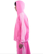 Person wearing a pink hoodie with three white stripes on a white background