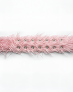 A close-up of a light pink faux fur trim with silver metal grommets, laid horizontally against a plain white background.